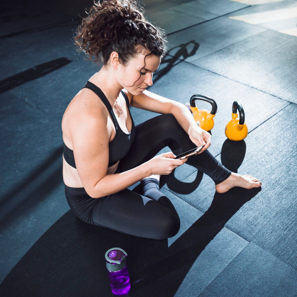 young-woman-using-cellphone-gym